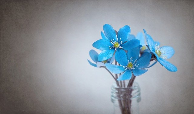 A blue glass vase with some flowers inside of it